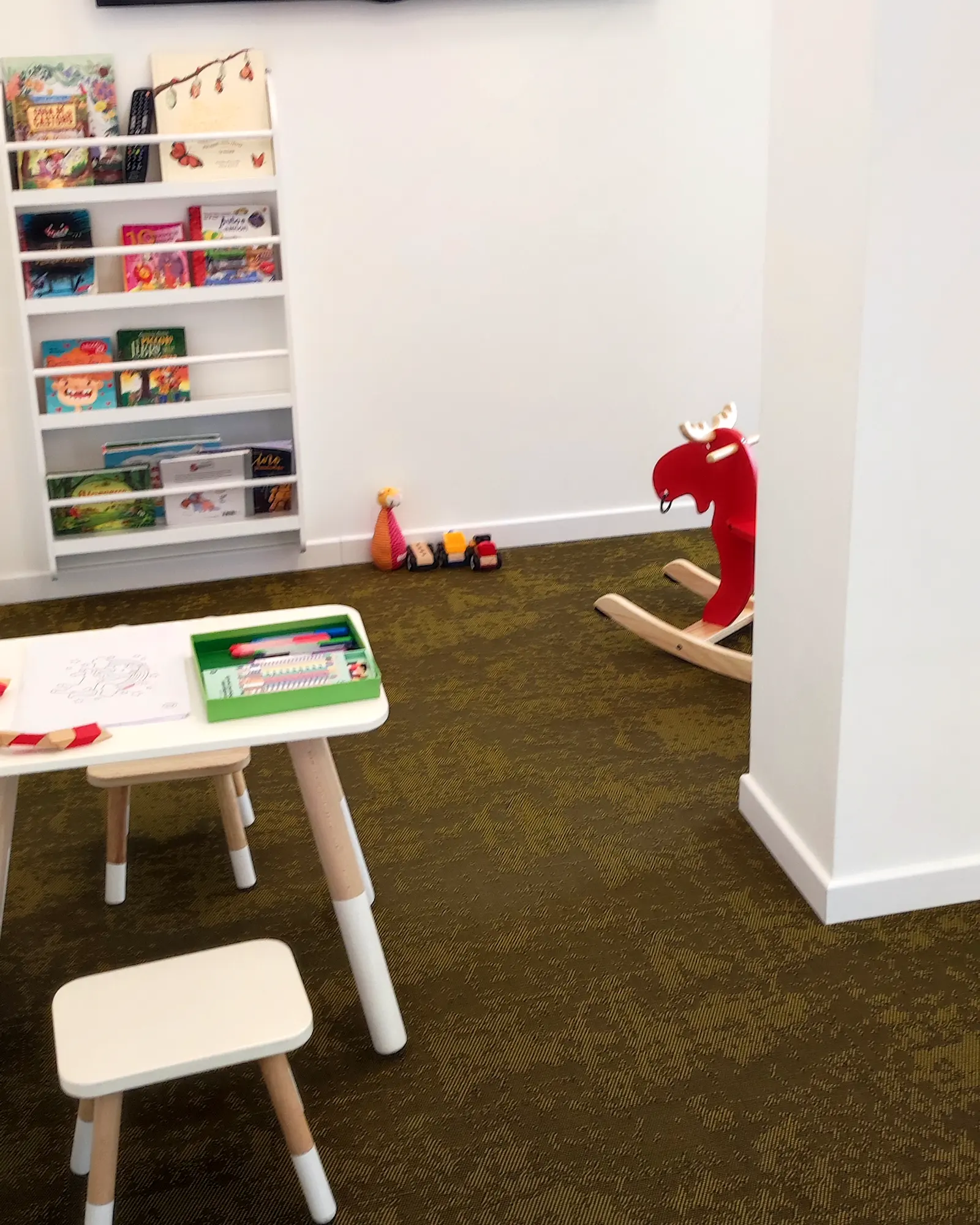 L'angolo dei bambini: la libreria coi libri illustrati, il cavallo a dondolo a forma di alce, il tavolino coi colori.